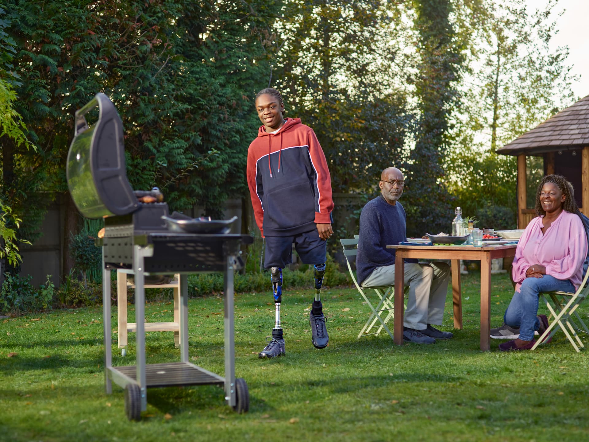 Young man with prosthetic legs having a BBQ with his family